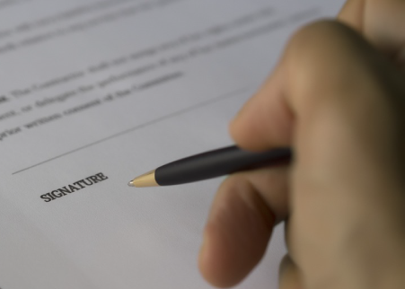 person signing a signature line on a document